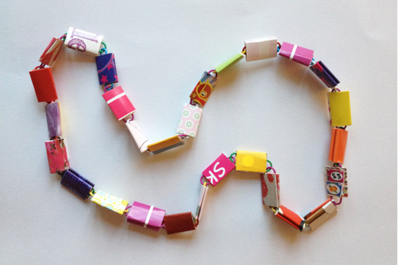 Farverig halskæde af go-cards og clips. Perfekt i længden til en barnehals. I frække røde, lilla, pink, gule og orange farver. 65 cm. 150 kr. Fotograf: Susanne Randers