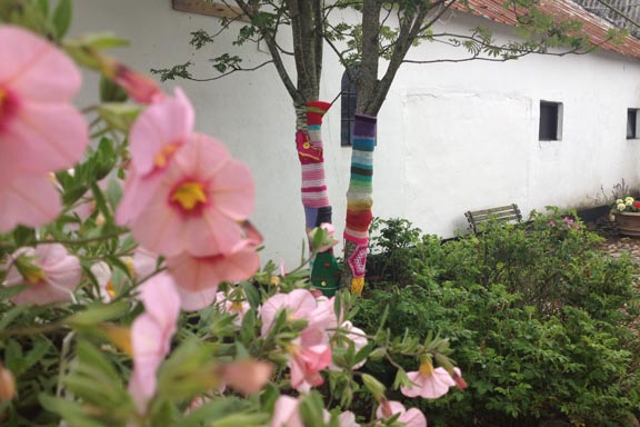 mitkrearum.dk kreativitet 100 yarnbombing på Højgården regnbuestrik og lapper fra familie og venner med blomster i forgrunden.jpg